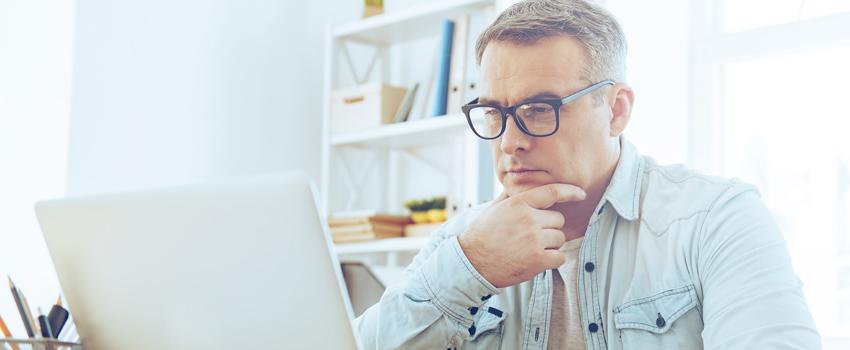 Man with glasses on working on laptop